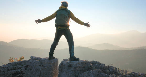 istock Mature man bridges gap on rock summit 2188325702