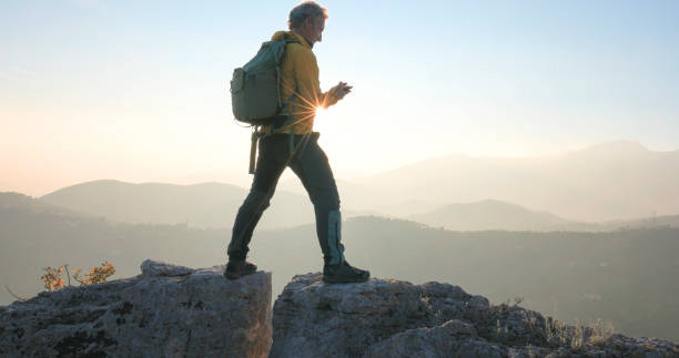 istock Mature man bridges gap on rock summit 2188325726