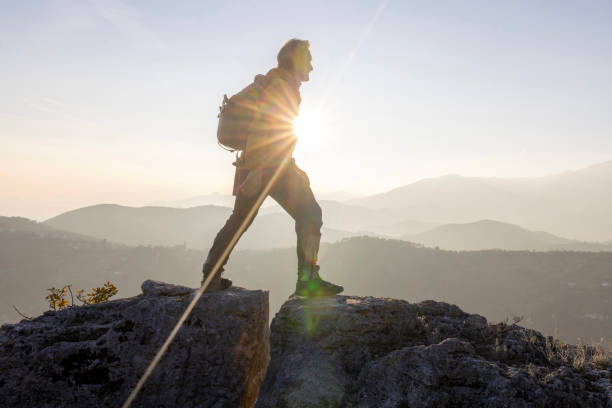 istock Mature man bridges gap on rock summit 2188325754