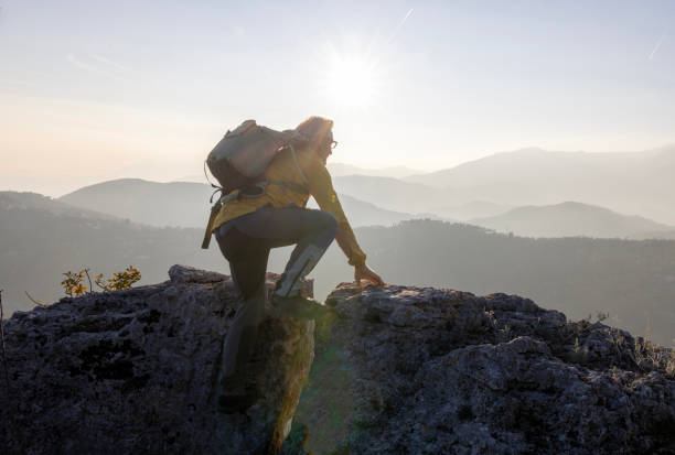 istock Mature man climbs onto gap on rock summit 2188325755