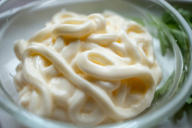 pouring mayonnaise into small glass container in restaurant in close-up slow motion