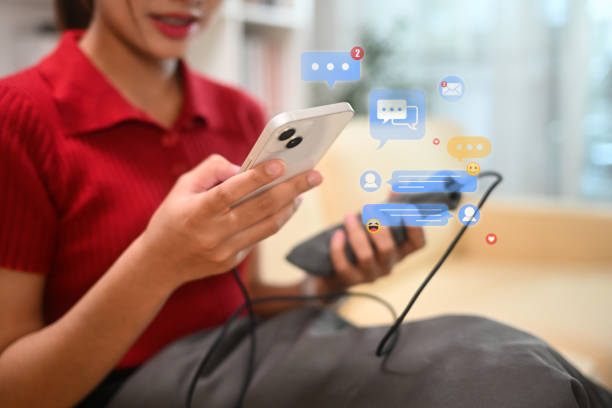 istock Smiling woman using smartphone surrounded by digital chat icons and notification bubbles 2188327230