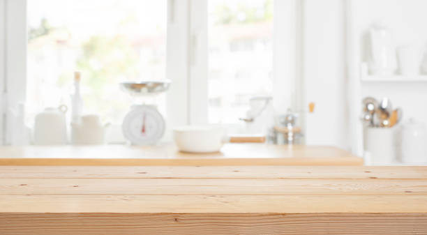 istock Kitchen table background with wooden counter top on blur abstract window sill interior 2188328310