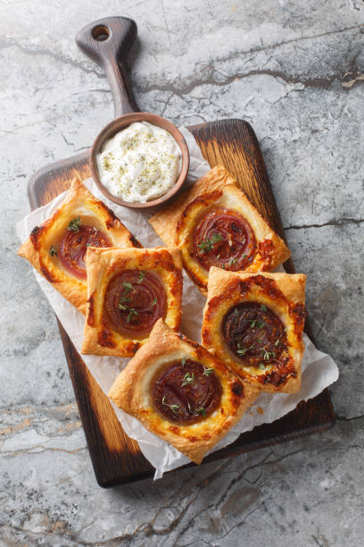 istock Puff mini tarts with caramelized red onion close-up on a wooden board. Vertical top view 2188333854
