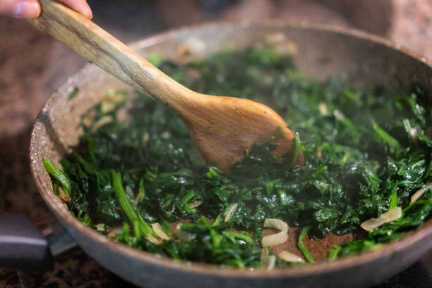 Spinach,garlic and onion sauteed in a frying pan, Spinach ,garlic and onion sauteed in a frying pan, preparing vegetarian meal, fresh homemade food spinach stock pictures, royalty-free photos & images
