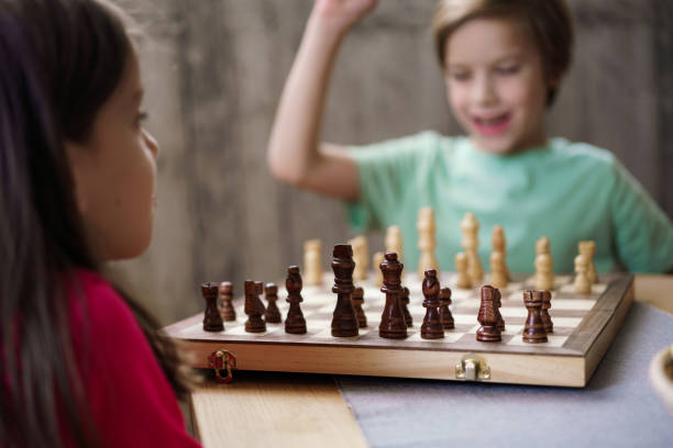 Happy boy and girl playing chees game on the table at home
