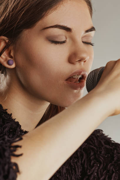 istock Young woman singing with closed eyes into a microphone 2188340224