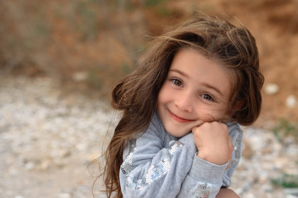 A young girl holding a rock with curiosity, capturing the innocence and wonder of childhood in a natural setting.