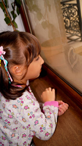 little girl drawing heart on the window. High quality photo