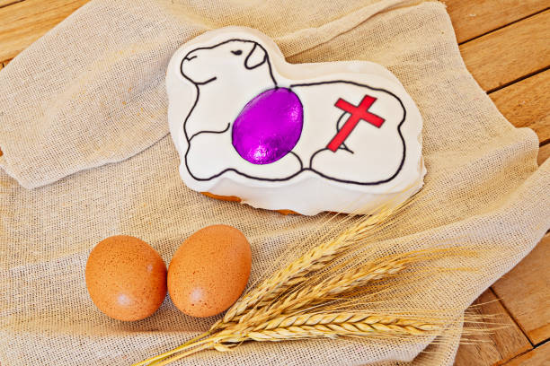 Traditional Maltese Easter lamb figolla cake with cross design, purple accent, and brown eggs on rustic wooden table