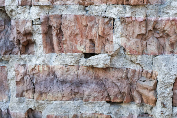 Close-Up of an Aged Brick Wall with Cracks and Texture. Detailed view of an old brick wall, showing natural cracks and weathered surfaces, ideal for backgrounds or architectural themes.