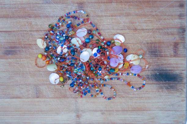Big bunch of multicolored African beadwork laying on a brown wooden surface.