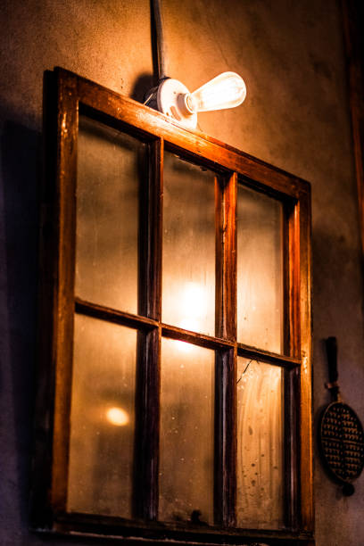 istock Rustic Wooden Window With Soft Ambient Light and Vintage Filament Bulb on a Textured Wall Creating Cozy Warmth and Nostalgic Atmosphere in a Traditional Home Setting 2188354188