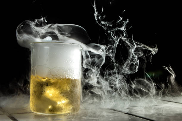White smoke is coming out of a beaker containing a yellow chemical liquid during a chemical reaction in a laboratory
