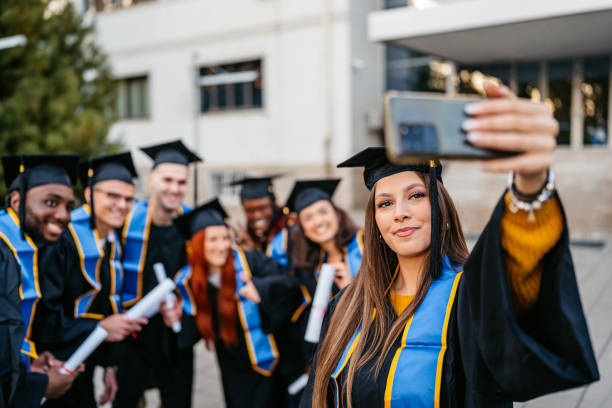 istock Students In Graduation Gowns Taking Selfies Using Phone On The University Campus 2188357152