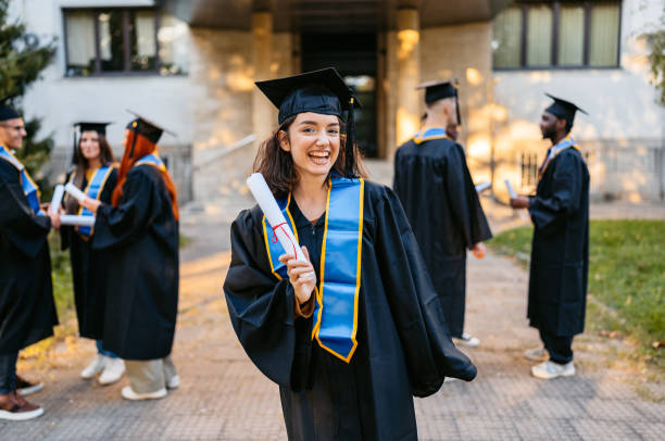 istock Young Female Student In Graduation Gown Standing On The University Campus 2188357257