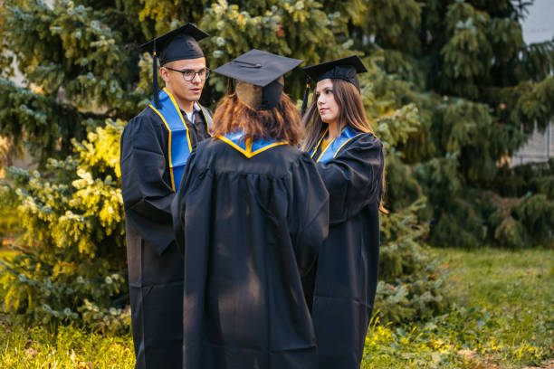 Group of students in graduation gowns talking on the university campus outdoors.