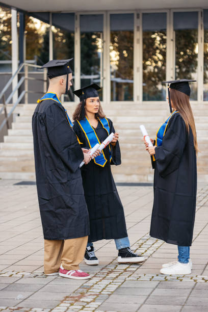 istock Students In Graduation Gowns Talking On The University Campus 2188359621