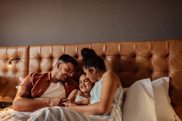 istock Couple playing with daughter on hotel bed 2188360282