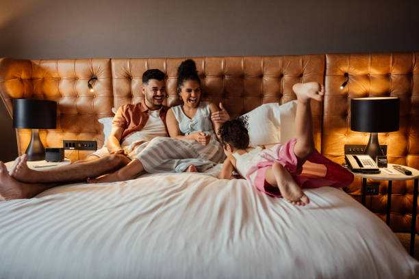 Couple playing with daughter on hotel bed