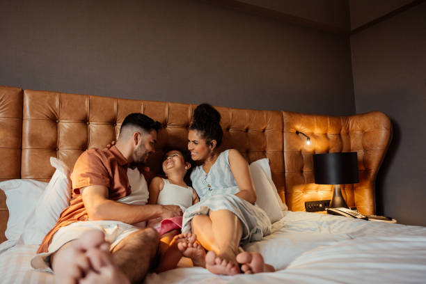 istock Couple playing with daughter on hotel bed 2188360344