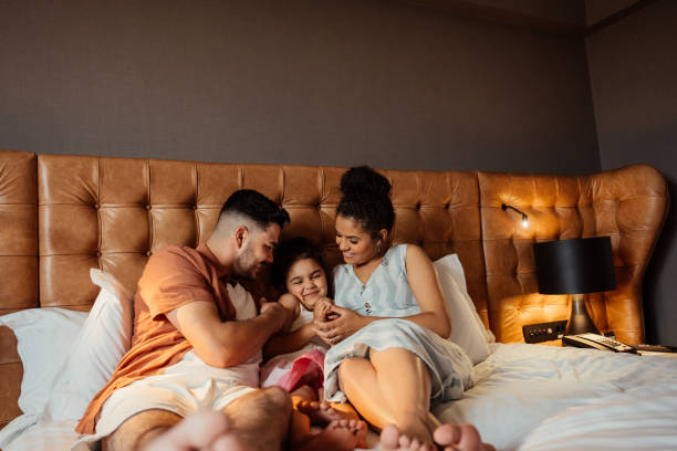 istock Couple playing with daughter on hotel bed 2188360353