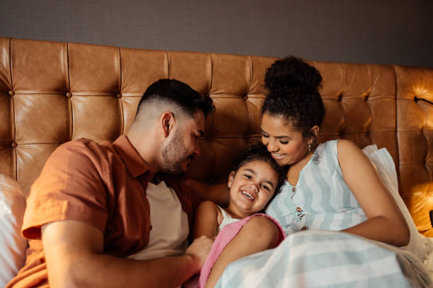 istock Couple playing with daughter on hotel bed 2188360579