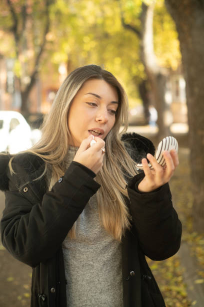 istock Young blonde on the street applying lip balm 2188363549