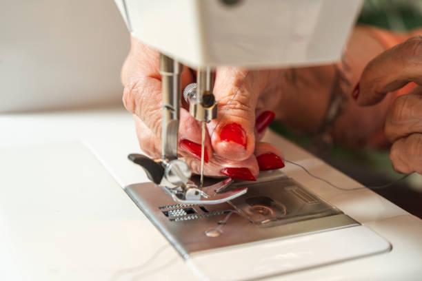 Seamstress threading the sewing machine needle before starting.