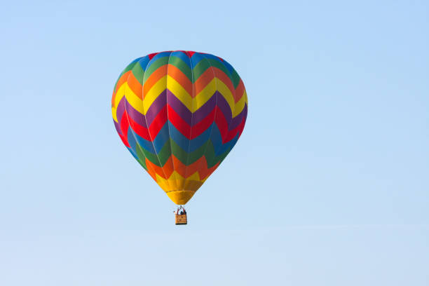 Brightly colored hot air balloon soars gracefully against a serene blue sky, offering a picturesque view of air travel