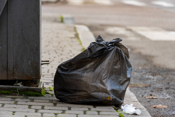 istock Garbage bags rest beside a waste container on a cobblestone path, showcasing the ongoing challenge of litter in urban settings. Effective recycling and disposal are essential for environmental health 2188370204