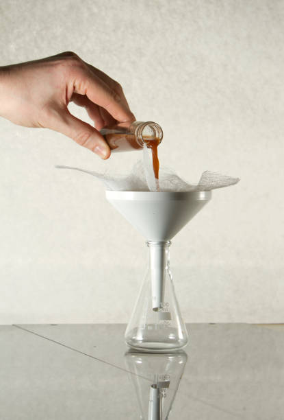 istock Scientist pouring brown liquid into filtering funnel in laboratory 2188370251