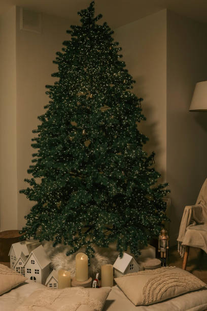 istock Minimalistic Christmas interior with a lit Christmas tree, soft pillows, glowing candles, and small decorative houses, creating a cozy and festive atmosphere 2188371615