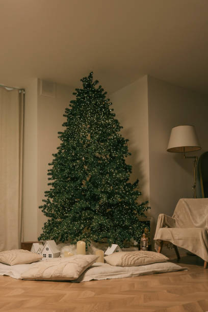 istock Minimalistic Christmas interior with a lit Christmas tree, soft pillows, glowing candles, and small decorative houses, creating a cozy and festive atmosphere 2188371617