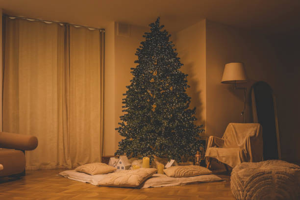 istock Minimalistic Christmas interior with a lit Christmas tree, soft pillows, glowing candles, and small decorative houses, creating a cozy and festive atmosphere 2188371622
