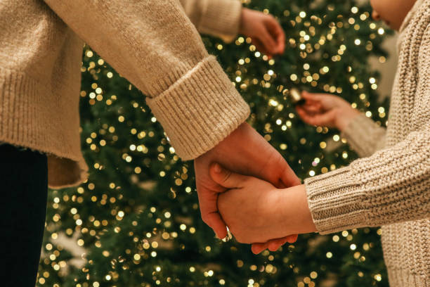 istock Parent and child decorating a Christmas tree together, holding hands while hanging an ornament. A warm and emotional family moment captured during the holiday season 2188371627