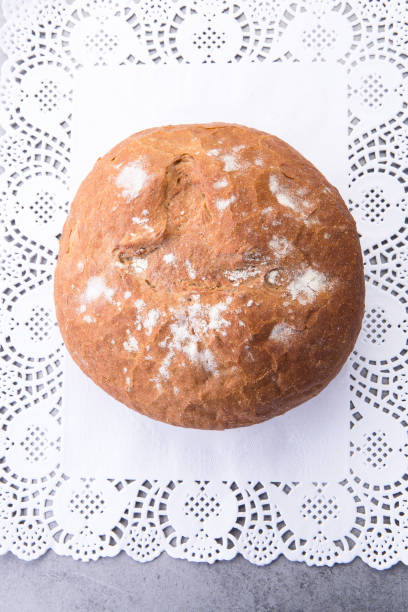 istock Round loaf of bread resting on decorative white paper doily 2188375366