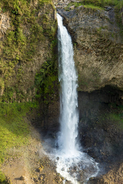 istock Waterfall cascading down rocky cliff in lush green mountain landscape 2188375497