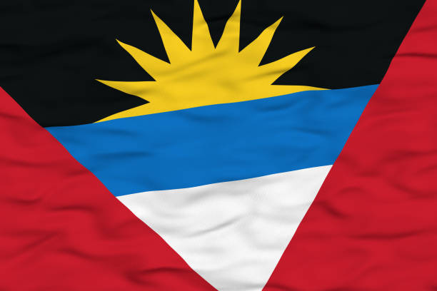 The national flag of Antigua and Barbuda depicted waving in the wind, showcasing a vibrant design with a rising sun, blue and white stripes, and red triangles. The black represents the African heritage, the blue symbolizes hope, the white for the beaches, and the rising sun for a bright future.