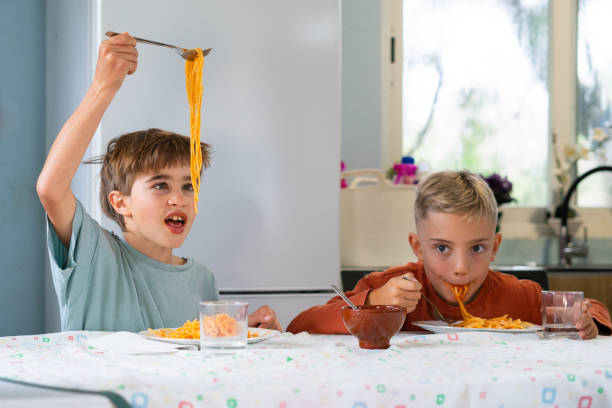 istock Children having fun while eating spaghetti with tomato sauce at home 2188379002