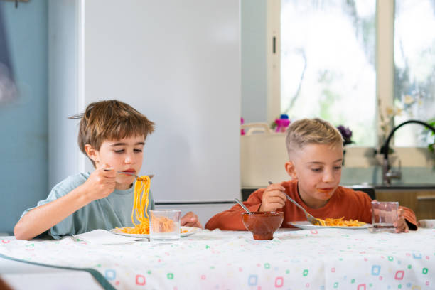 istock Two brothers eating spaghetti with tomato sauce at home 2188379003