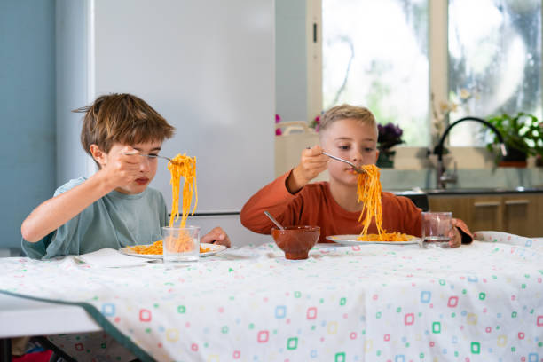 istock Two brothers eating spaghetti with tomato sauce at home 2188379004