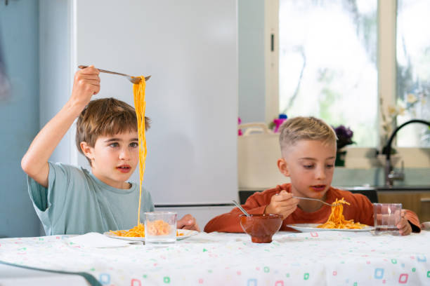 istock Two brothers eating spaghetti with tomato sauce at home 2188379007