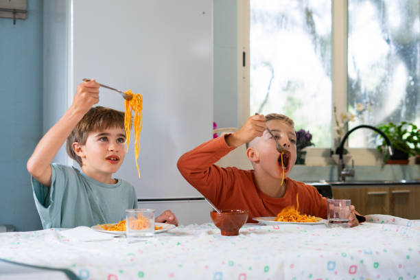istock Two brothers eating spaghetti with tomato sauce at home 2188379016