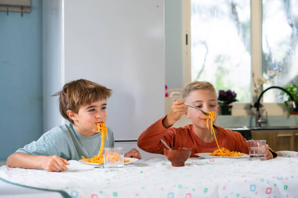 istock Two brothers eating spaghetti with tomato sauce at home 2188379017