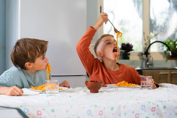 istock Children eating spaghetti with tomato sauce at home 2188379020
