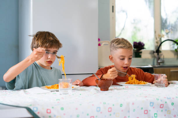 istock Two brothers eating spaghetti with tomato sauce at home 2188379034