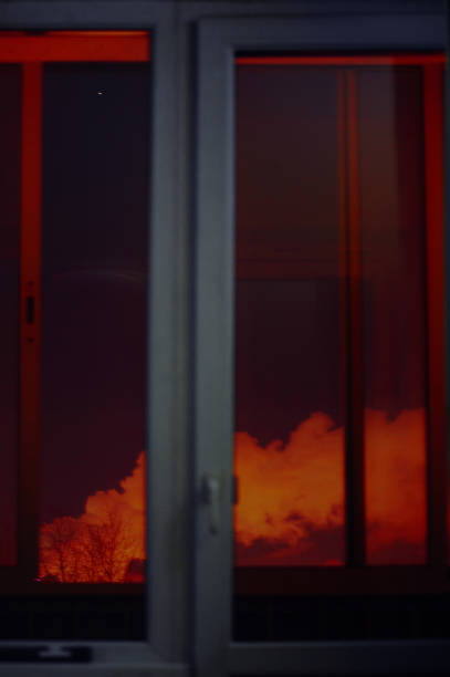 A bright fire is clearly visible through a window during the night, casting a warm glow that illuminates the surroundings