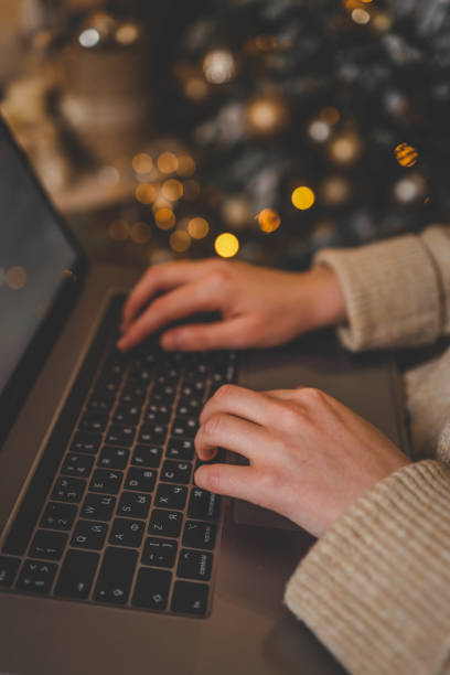 istock Hands typing on a laptop with a beautifully glowing Christmas tree in the background, creating a cozy and festive atmosphere indoors 2188383424