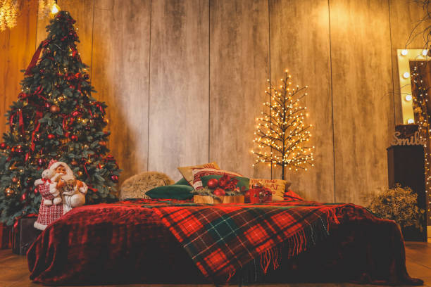 The warm glow of lights illuminates a cozy room adorned for the holidays. A beautifully decorated Christmas tree stands near the window, creating a festive atmosphere.